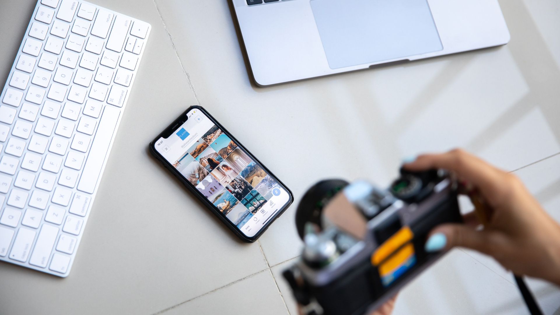 Photography workspace with keyboard, laptop, smartphone, and camera